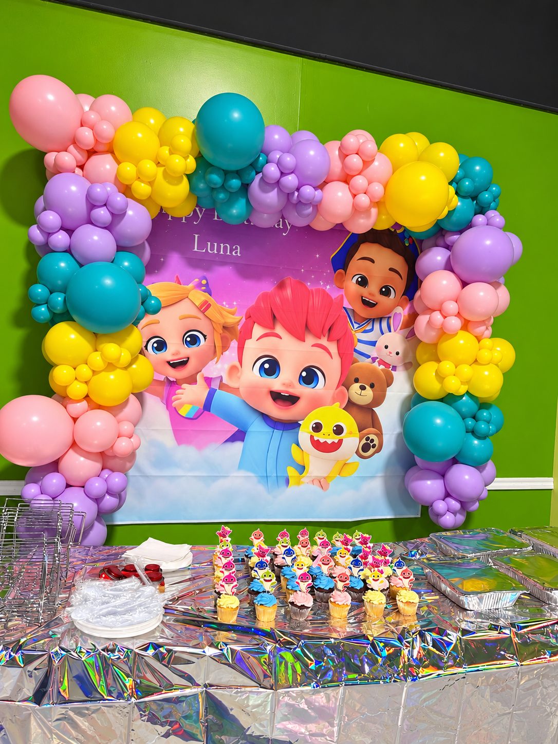 Colorful balloon arch around a personalized Luna birthday banner, with a dessert table, at FunZ Westfield